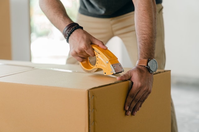 Cropped image of a person taping a moving box closed